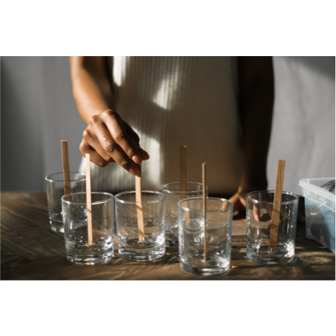 A woman putting candle wicks into glass jars