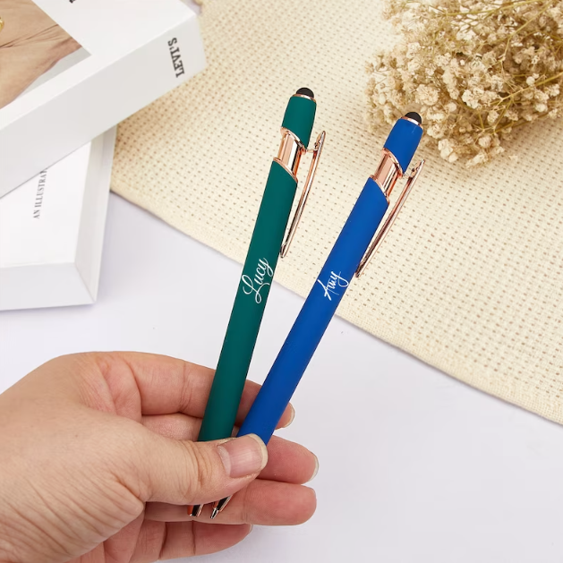 A hand holding two pens at the nib to show how big they are